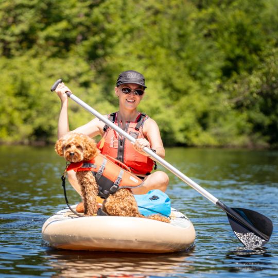 Jeune fille avec son chien sur une planche à pagaie à l'été chez Canots Légaré